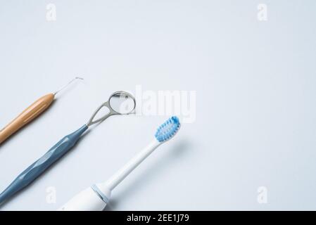 Dentist tools on a blue light background: a dental probe, a dental mirror and an electric brush. Stock Photo