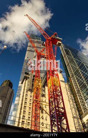 Looking up at construction work of 8 Bishopsgate with skyscraper 22 bishopsgate towering into the sky against a deep blue sky with fluffy clouds Stock Photo
