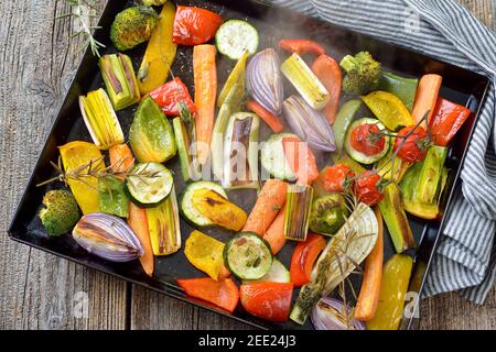 Baked mixed colorful vegetables on a baking sheet  just coming steaming out of the oven Stock Photo