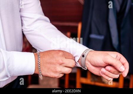 The groom fastens a button on the sleeve of his shirt Stock Photo