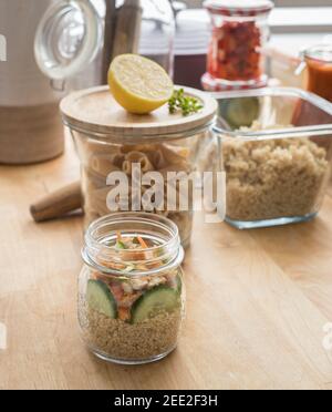 Batch cooking containers full of delicious homemade meal. cucumber slices with carrot and quinoa are in the forefront jar. Stock Photo