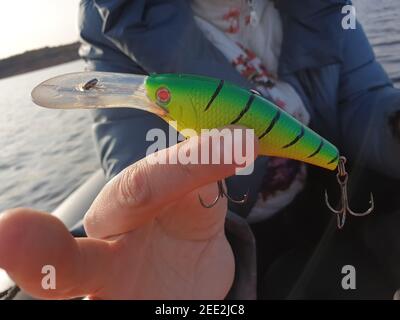 fishing wobbler in hand on a river background close-up place for