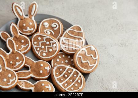 Easter cookies in the shape of bunnies and eggs on a gray plate and a grey stone background,Close up Stock Photo