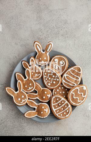 Easter cookies in the shape of bunnies and eggs on a gray plate and a grey stone background,Top view and copy space Stock Photo