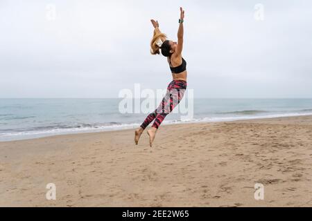 Fitness athletic woman jumping on the beach during working out exercises.Concept of happiness, yoga and training lifestyle. Stock Photo