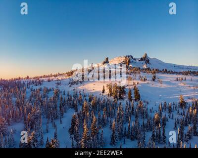 Colorful winter sunset in Sheregesh ski resort mountains with clouds. Aerial top view forest Russia. Stock Photo