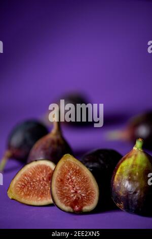 Still life with fresh figs on a purple seamless background. Stock Photo