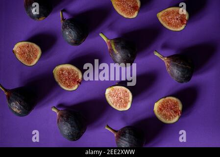 Still life with fresh figs arranged in a repeating pattern on a purple seamless background.  Overhead view. Stock Photo