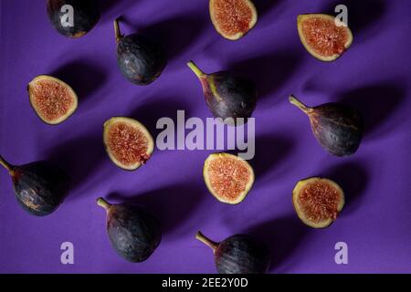 Still life with fresh figs arranged in a repeating pattern on a purple seamless background.  Overhead view. Stock Photo