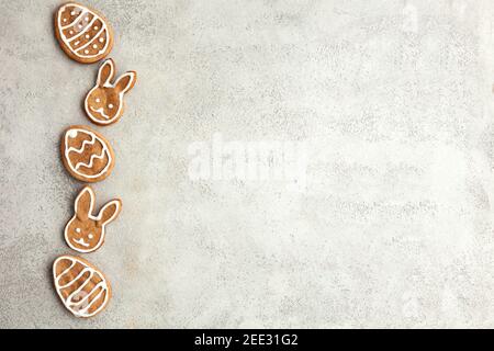 Easter decorated cookies in the shape of a bunny and eggs are laid out in a row on a gray background. Top view Stock Photo