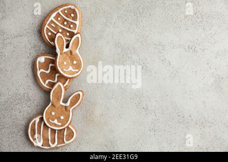 Easter decorated cookies in the shape of a bunny and eggs are laid out in a row on a gray background. Top view Stock Photo