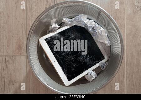 Modern tablet with highly broken screen in the litter bin. Top view. Stock Photo