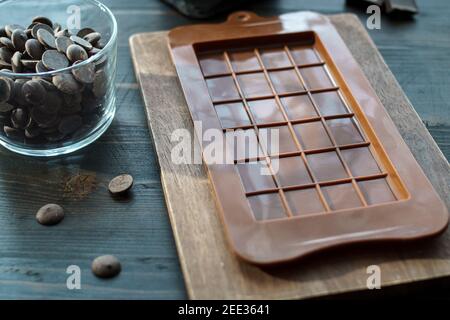Chocolate bar mold silicone and chocolate callets on table. Low shallow focus Stock Photo