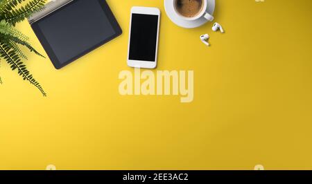 Flat lay top view office desk working space with tablet on yellow background. Copy space. Stock Photo