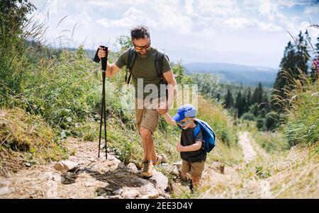 Father with small son hiking outdoors in summer nature, walking. Stock Photo