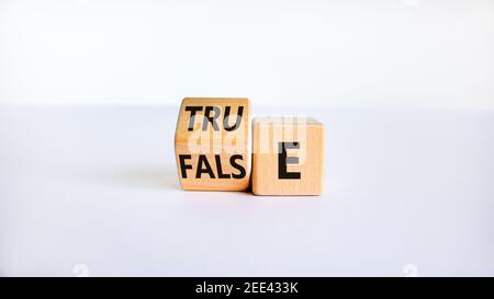 False or true symbol. Turned a wooden cube and changed the word 'false' to 'true' or vice versa. Beautiful white table, white background, copy space. Stock Photo
