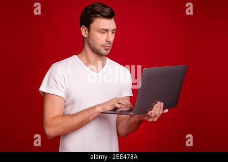 Photo portrait of young programmer working with laptop concentrated focused isolated vibrant red color background Stock Photo