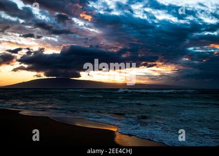 Dramatic clouds and sky over stormy sea at sunset with island on horizon. Stock Photo