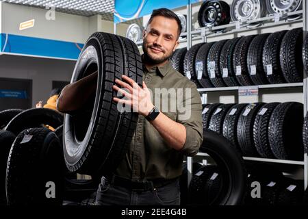 customer tire fitting in the car service, auto mechanic checks the tire and rubber tread for safety, concept: repair of machines, fault diagnosis, rep Stock Photo