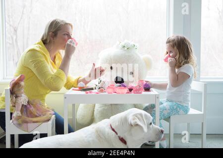 A little girl having a pretend tea party with her mom. Stock Photo