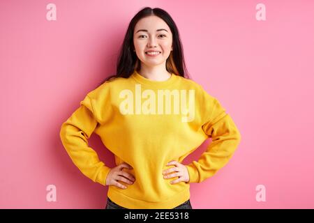 brunette posing at camera, isolated over pink background. portrait of young lady in yellow casual wear. people concept Stock Photo