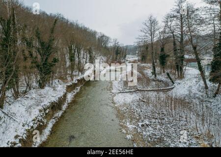 Aerial view of riverbed in mountain gorge. Winter river in snow weather. Stock Photo