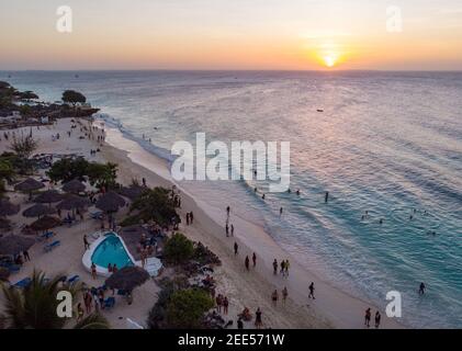 Aerial Shot on Zanzibar a beautiful sunset with people Walking on the Nungwi beach in Zanzibar in Tanzania Stock Photo