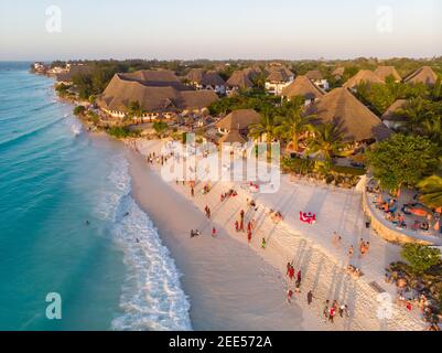 Aerial Shot on Zanzibar a beautiful sunset with people Walking on the Nungwi beach in Zanzibar in Tanzania Stock Photo