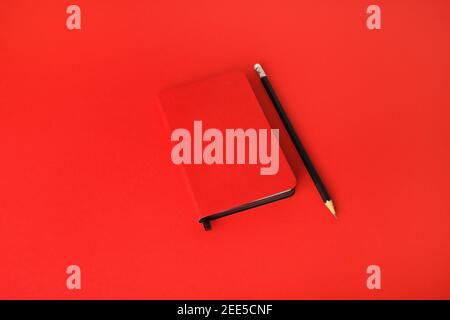 Red notebook and pencil on red paper background. Template for branding identity. Stock Photo