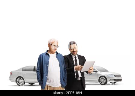 Car salesman and a mature customer looking at a tablet in a car showroom isolated on white background Stock Photo