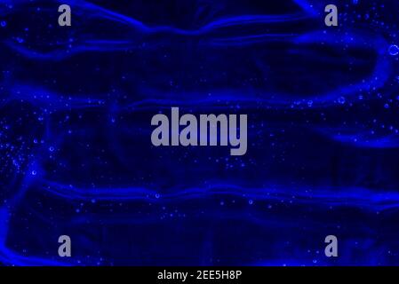 Transparent dark blue Gel background or pattern with light blue neon lights. Gel on dark blue background Virus protection or cosmetics concept Stock Photo