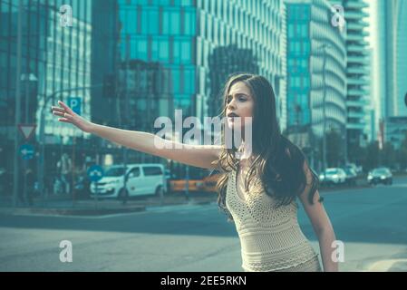 Hailing taxi. Woman catch taxicar on city street. Travel, tourism and people concept. Catching taxi on street or hitch-hiking. Gesture transportation, Stock Photo