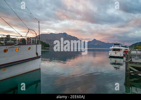 Queenstown New Zealand - March 1 2015; Tourist boat TSS Earnslaw and luxury launch parked at pier in township by Lake Wakatipu in morning light before Stock Photo