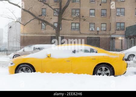Yellow Car Covered in Snow with Buildings in the Background on City Street. Feelings of a snow day and traffic.  Ideas of working from home. Stock Photo