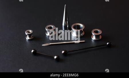 Set for piercing on a dark background, ear tunnels, tunnels and earrings for the ears and tongue Stock Photo