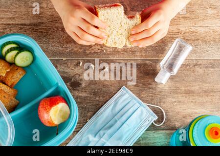 Flat lay image with eating lunch at school concept during the phased reopening after COVID-19 pandemic closures. Snack in containers as well as water Stock Photo