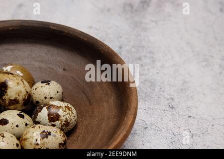 fresh quail eggs from the farm in a plate of brown clay on a gray marble table.  Stock Photo