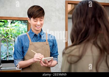 Young Asian man coffee shop staff taking order from the customer at the counter Stock Photo