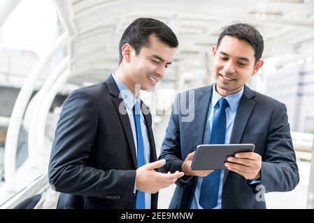 Young handsome businessmen discussing project on digital tablet computer outdoors Stock Photo