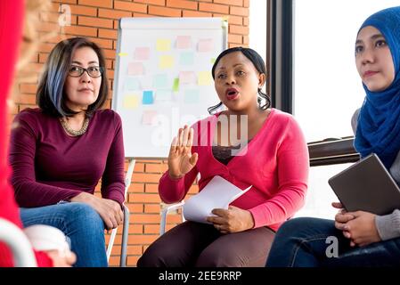 Multiethnic women in colorful casual clothes discussing in the group meeting Stock Photo