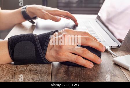 Chronic trauma to the wrist joint  in people using computer mouse may lead to disorders that cause inflammation and pain. A woman working on desk uses Stock Photo