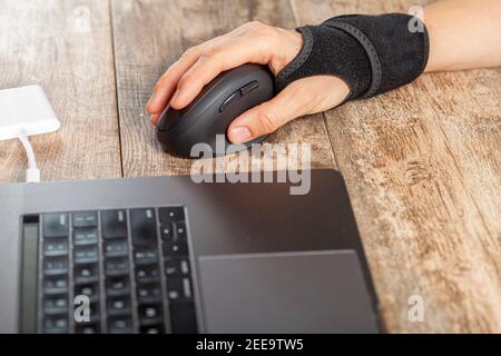 Chronic trauma to the wrist joint  in people using computer mouse may lead to disorders that cause inflammation and pain. A woman working on desk uses Stock Photo