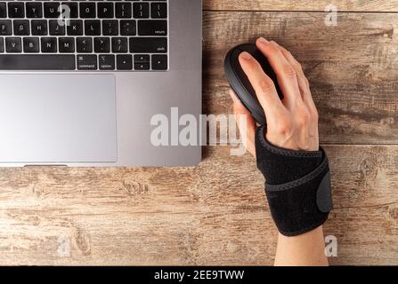 Chronic trauma to the wrist joint  in people using computer mouse may lead to disorders that cause inflammation and pain. A woman working on desk uses Stock Photo