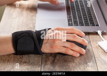 Chronic trauma to the wrist joint  in people using computer mouse may lead to disorders that cause inflammation and pain. A woman working on desk uses Stock Photo