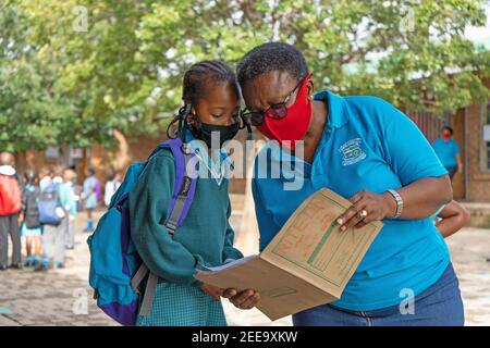 Johannesburg, South Africa. 15th Feb, 2021. A teacher checks a student's information at a primary school in Johannesburg, South Africa, Feb. 15, 2021. Over 20,000 public schools in South Africa were reopened in accordance with strict adherence to the COVID-19 protocol on Monday. Credit: Matthew Martin Brink/Xinhua/Alamy Live News Stock Photo