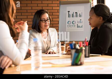 Group of multiethnic businesswoman leader team discussing project in meeting room Stock Photo