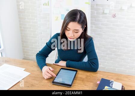 Asian female college student concentrating on reading digital e-book reader at the table Stock Photo