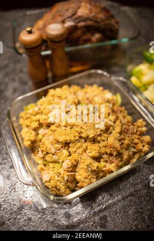 Traditional side dish of homemade stuffing with bacon for Thanksgiving or Christmas in a glass baking pan with salt and pepper shakers and rib roast i Stock Photo