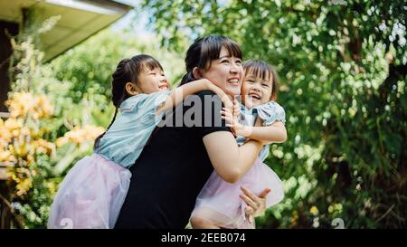Portrait of asian family of 2 cute kids (daughter) feeling happy and smiles while playing with mom. Concept for love of mother and family bonding Stock Photo