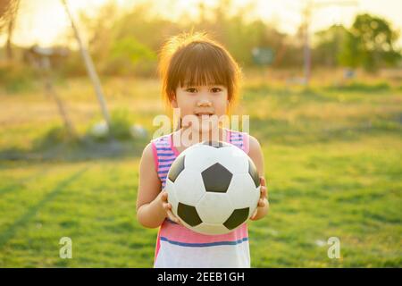 Happy and smile kids playing soccer football for exercise under the sunlight. Stock Photo